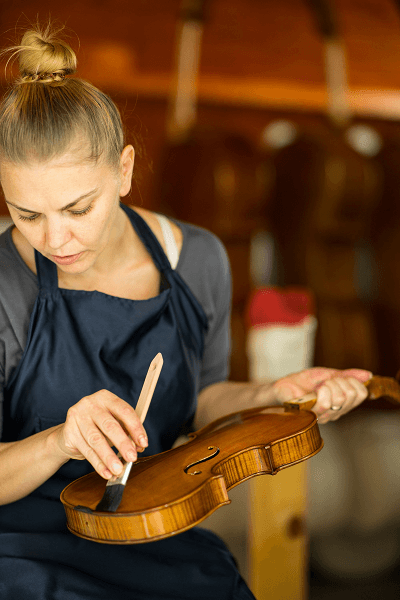 Ecaterina Simon applying varnish to a violin with precision