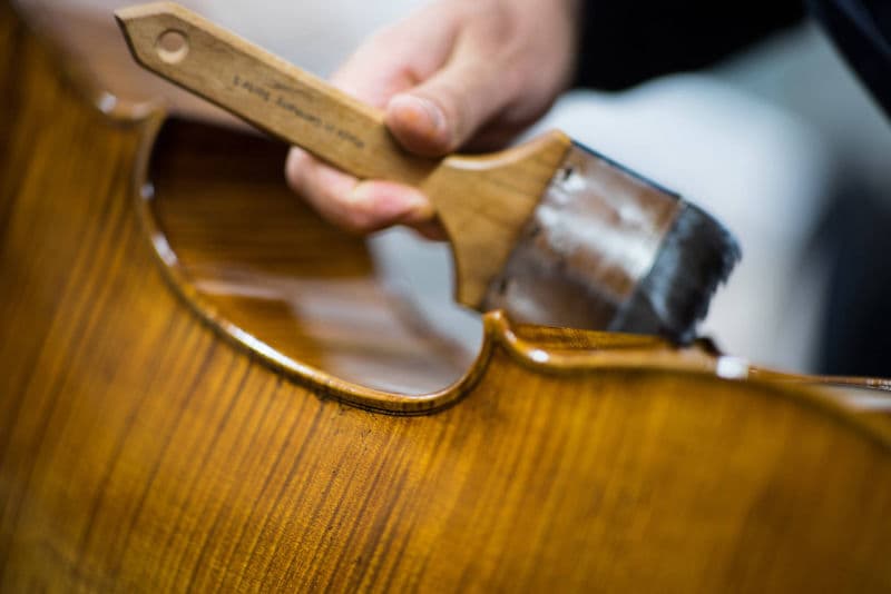 Close-up of hand applying varnish to an instrument
