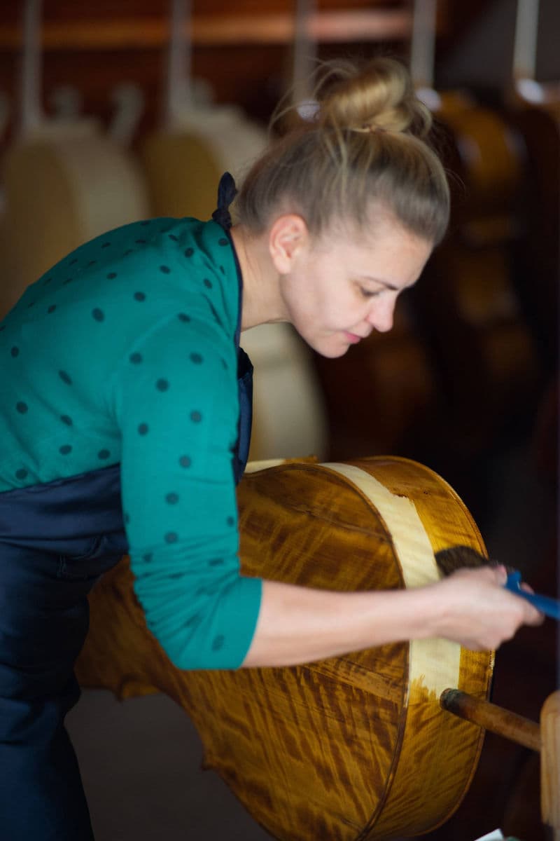 Ecaterina varnishing a cello body in the workshop